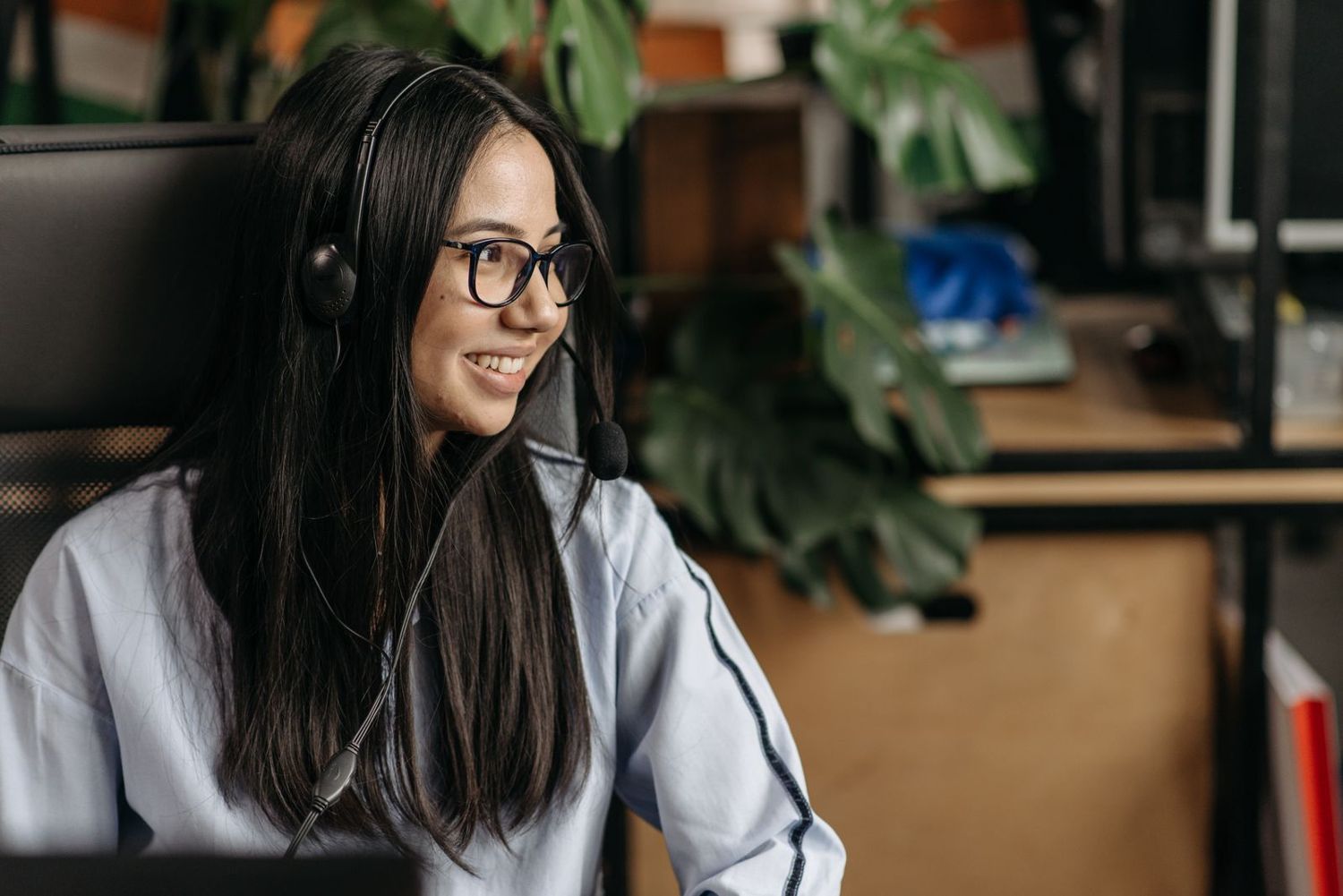 A smiling agent with a headset at her desk