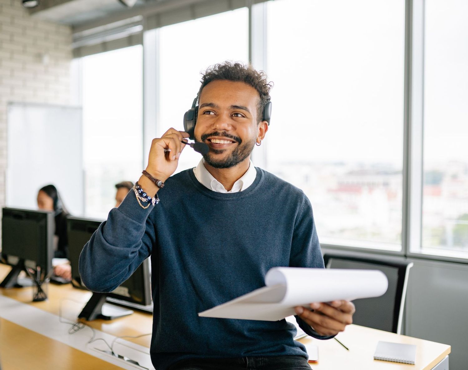 A smiling agent on a call holding his notes