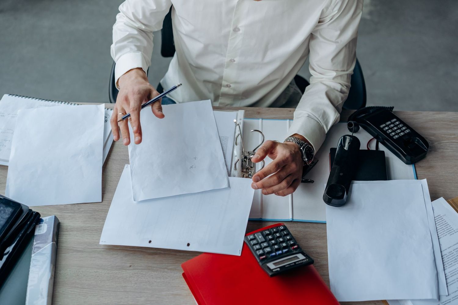 Paperwork being processed at a desk with a calculator
