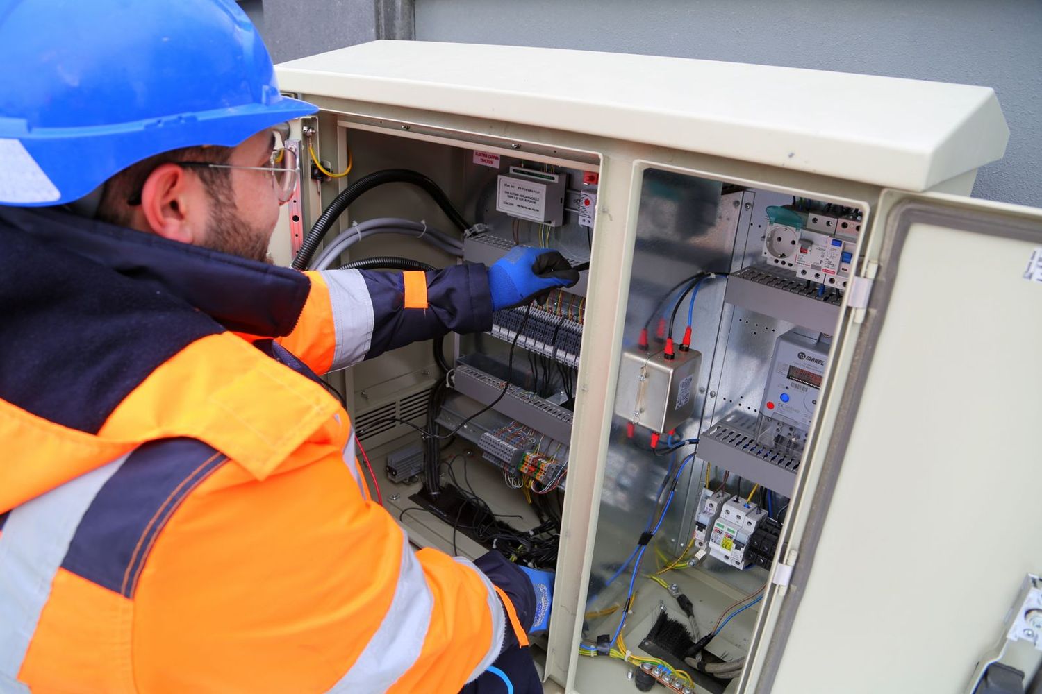 A utilities technician working on an electrical cabinet