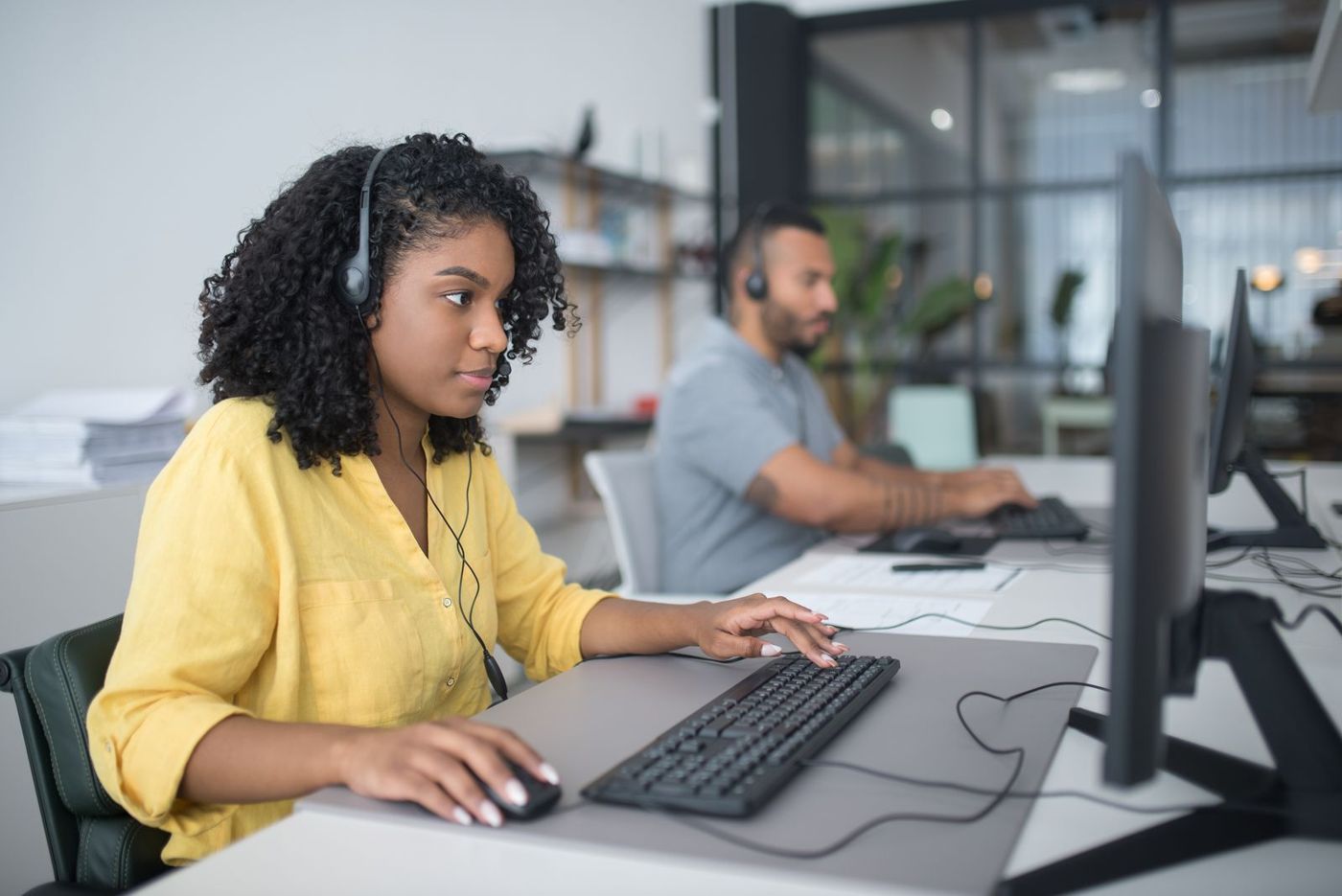 An agent working at her desk with a colleague behind her
