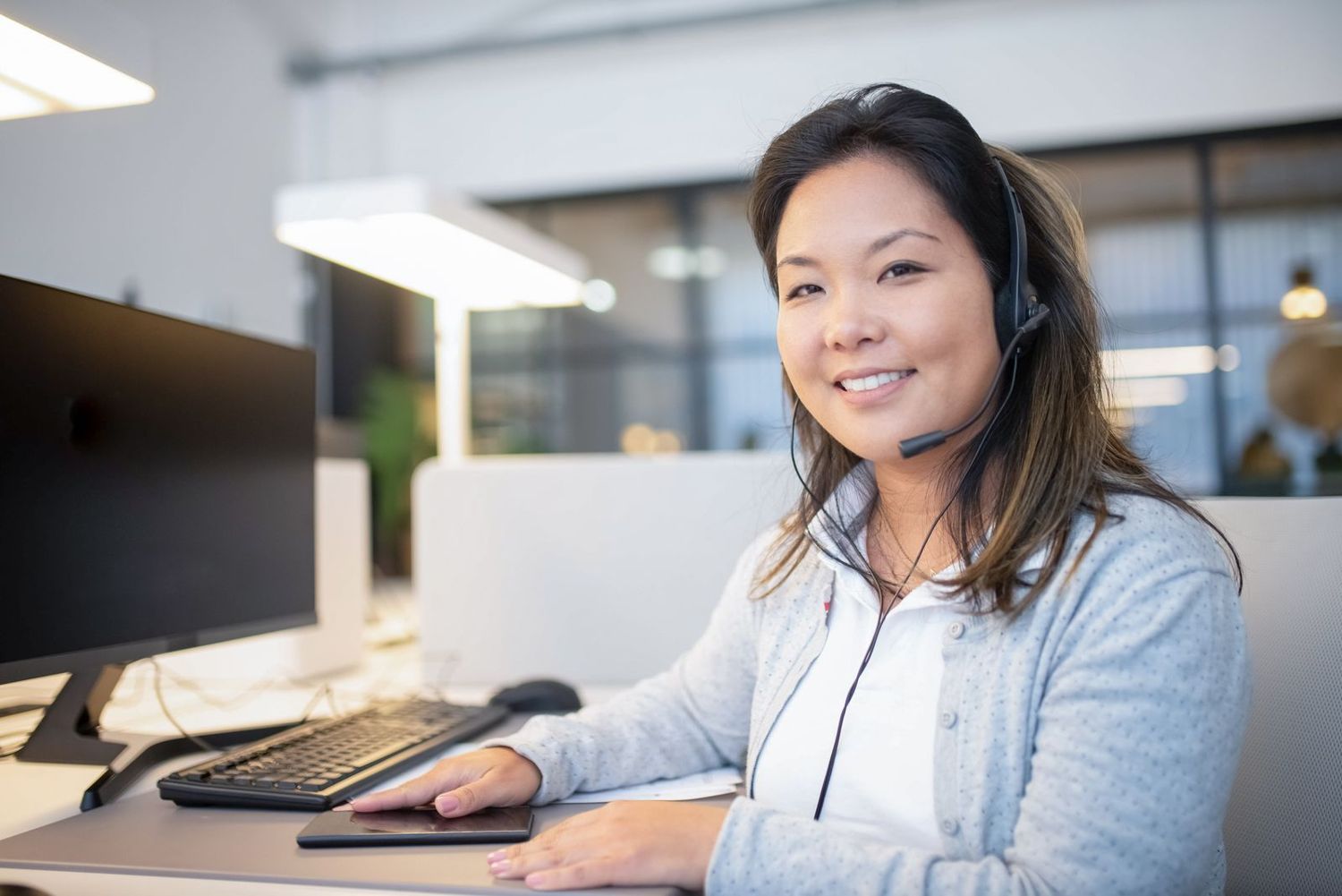 An agent with a headset smiling at her desk