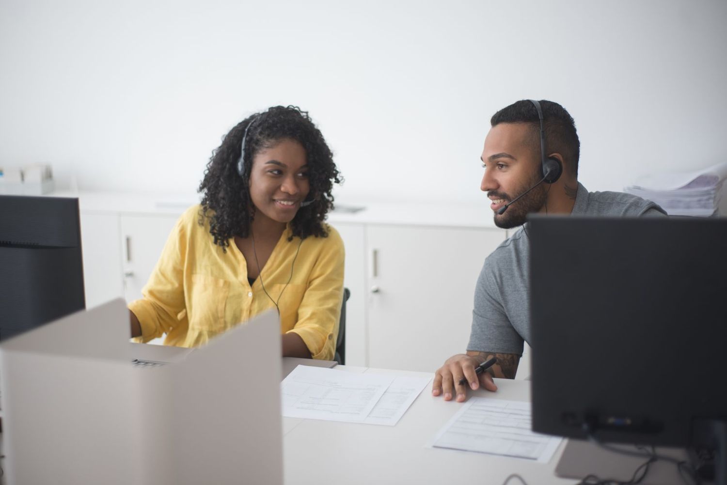 Two colleagues working side by side at a shared desk
