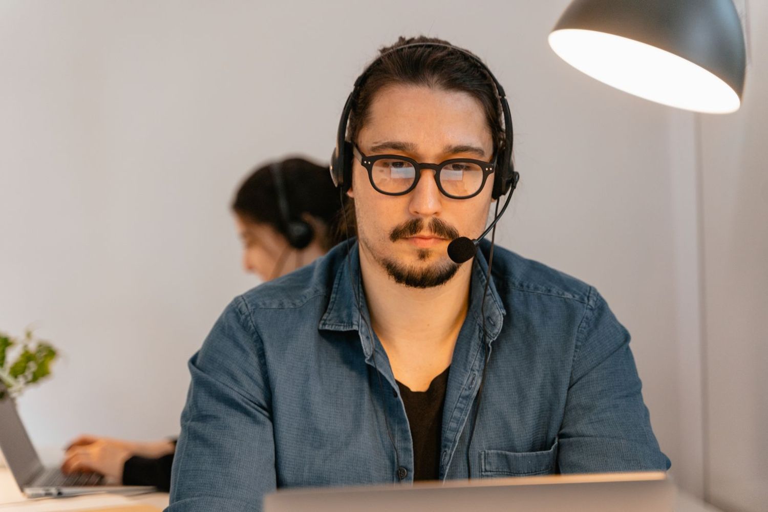 An agent with a headset working an evening shift under a desk lamp